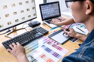 Team of young colleagues creative graphic designer working on color selection and drawing on graphics tablet at workplace, Color swatch samples chart for selection coloring.